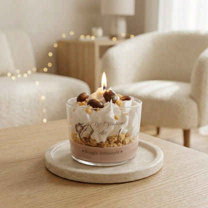 Bougie artisanale Eclat de Noisettes allumée, avec décor de cire façon chantilly blanche et ornements bruns, sur une table dans un salon cosy - Les Créations des A