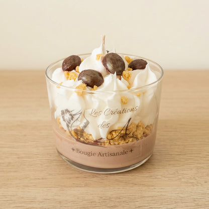Bougie artisanale Eclat de Noisettes dans un verre transparent, décorée de cire façon chantilly blanche, d’ornements bruns et d’éclats dorés, sur fond crème - Les Créations des A