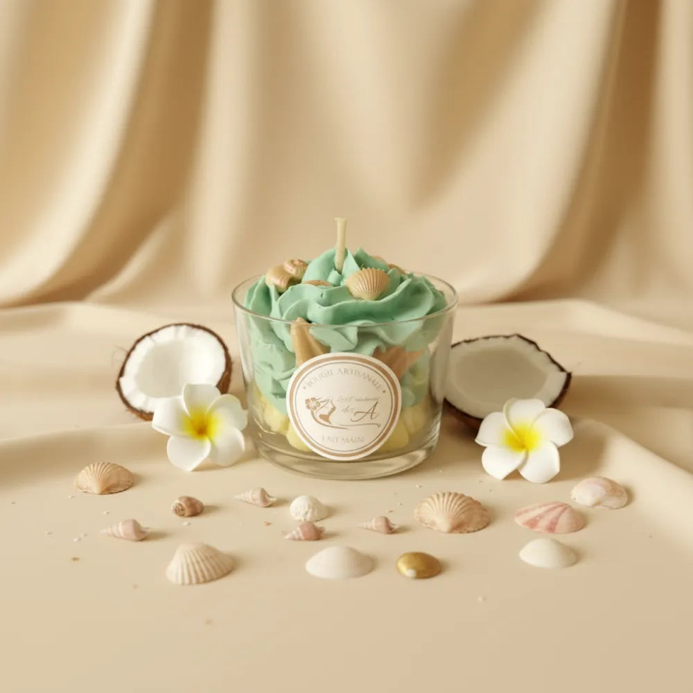 Bougie parfumée monoï, présentée avec noix de coco, fleurs de tiaré et des coquillages sur fond de tissu beige satiné - Les Créations des A