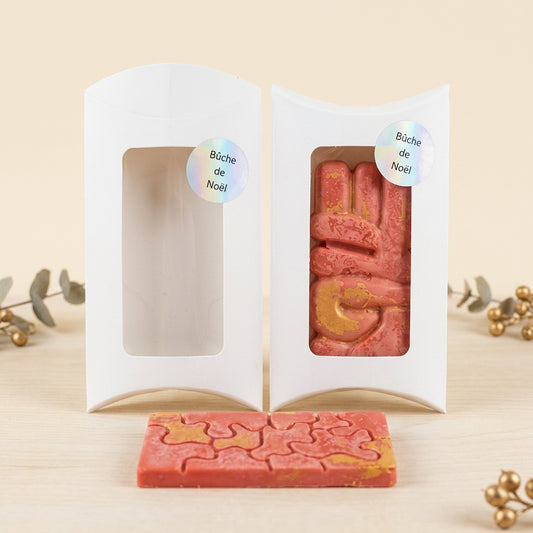 Fondants parfumés Bûche de Noël rose corail avec des détails dorés, présentés dans une boîte blanche à fenêtre et avec un fondant puzzle posé devant - Les Créations des A