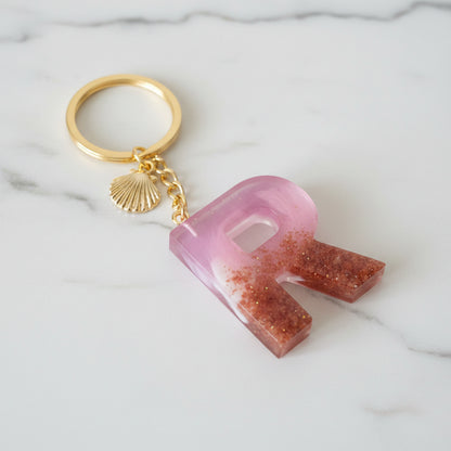 Porte-clé personnalisé lettre R en résine artisanale, collection Corail rose avec effet sable et breloque coquillage dorée - Les Créations des A