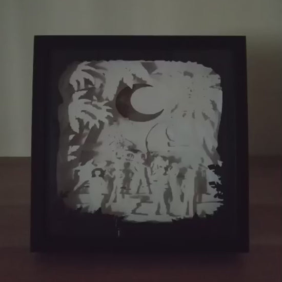 Shadow box lumineuse artisanale inspirée d'un univers de pirates. Décor multicouche représentant un équipage d'aventuriers, un grand navire et un paysage tropical avec éclairage LED - Les Créations des A