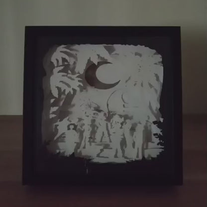 Shadow box lumineuse artisanale inspirée d'un univers de pirates. Décor multicouche représentant un équipage d'aventuriers, un grand navire et un paysage tropical avec éclairage LED - Les Créations des A