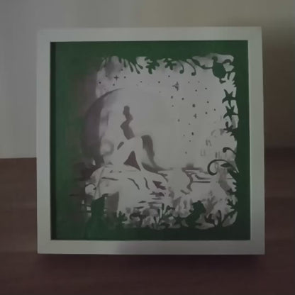 Shadow box lumineuse artisanale représentant une sirène assise au bord de l'eau dans un décor marin féérique. Création multicouche avec éclairage LED et ambiance océanique - Les Créations des A