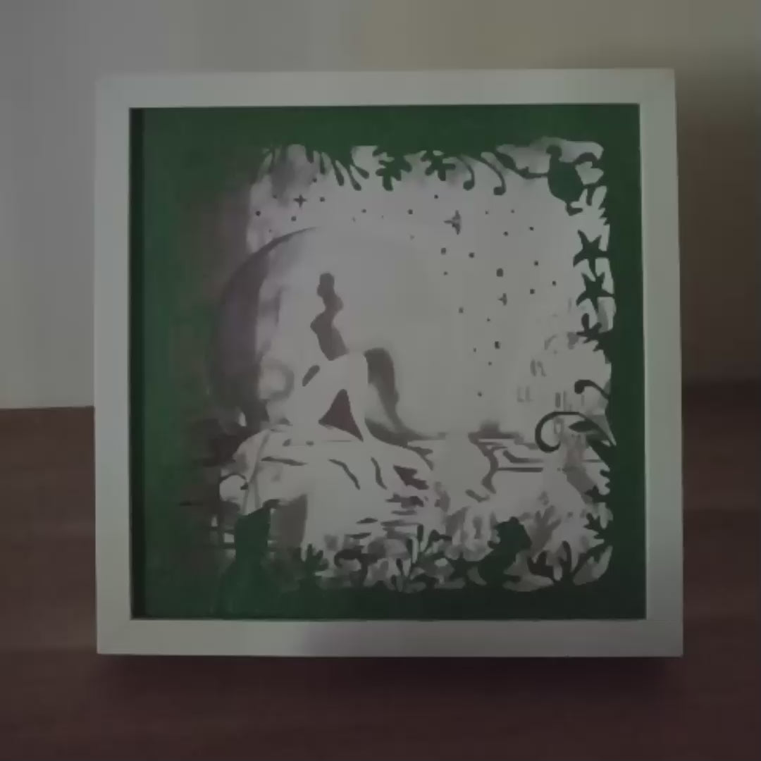 Shadow box lumineuse artisanale représentant une sirène assise au bord de l'eau dans un décor marin féérique. Création multicouche avec éclairage LED et ambiance océanique - Les Créations des A