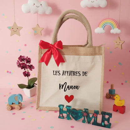 Sac en jute "Les affaires de Manon" avec cœur rouge et nœud rouge sur fond rose pastel – sac crèche fille - Les Créations des A