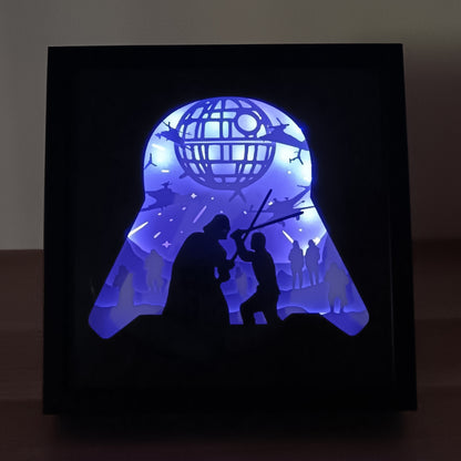 Shadow box lumineuse univers galactique avec duel légendaire, station spatiale et vaisseaux interstellaires en papier découpé - Les Créations des A
