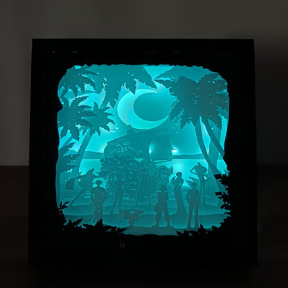 Shadow box lumineuse artisanale inspirée d'un univers de pirates. Décor multicouche représentant un équipage d'aventuriers, un grand navire et un paysage tropical avec éclairage LED - Les Créations des A